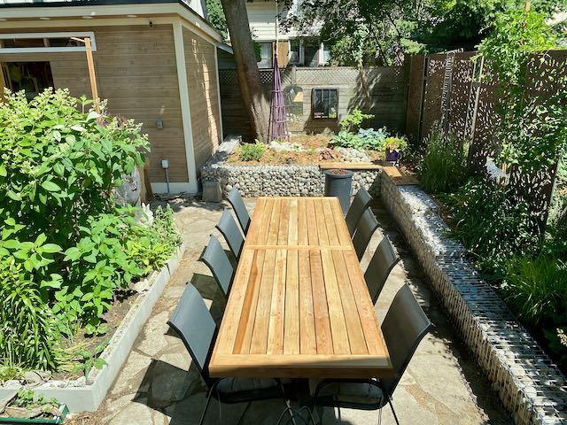Small urban garden with long dining table and eight chairs surrounded by raised beds